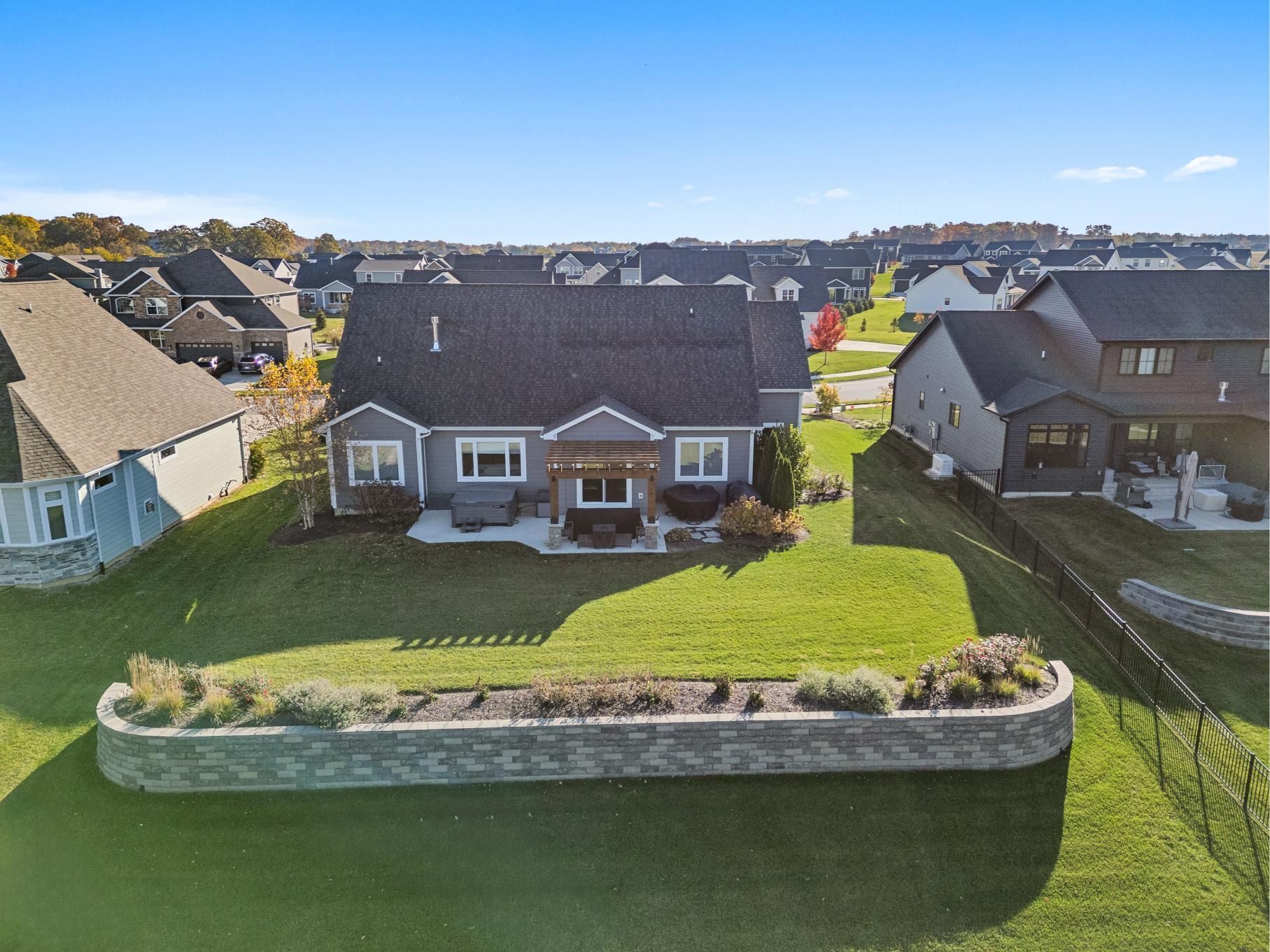 Suburban house with a dark roof, white exterior, and landscaped front yard under a clear blue sky