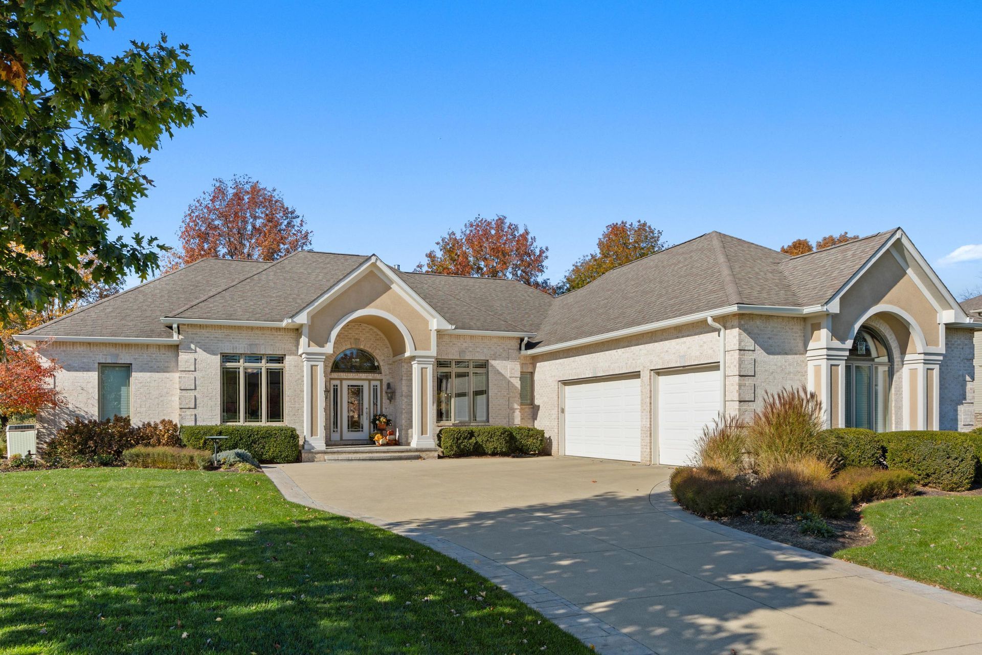 Single-story suburban house with a three-car garage, landscaped lawn, and a curved driveway