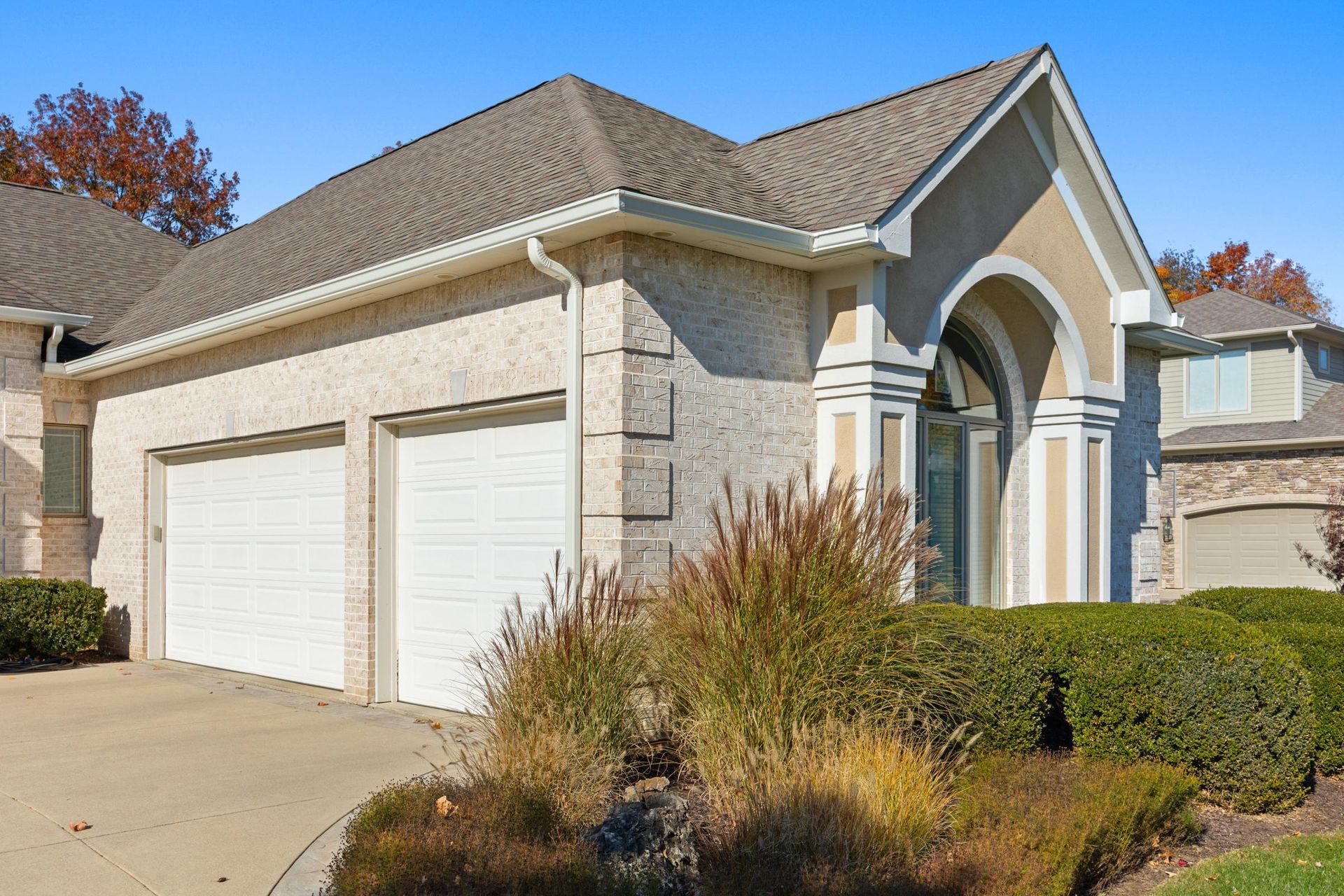 Suburban two-car garage with beige stone exterior and arched entryway