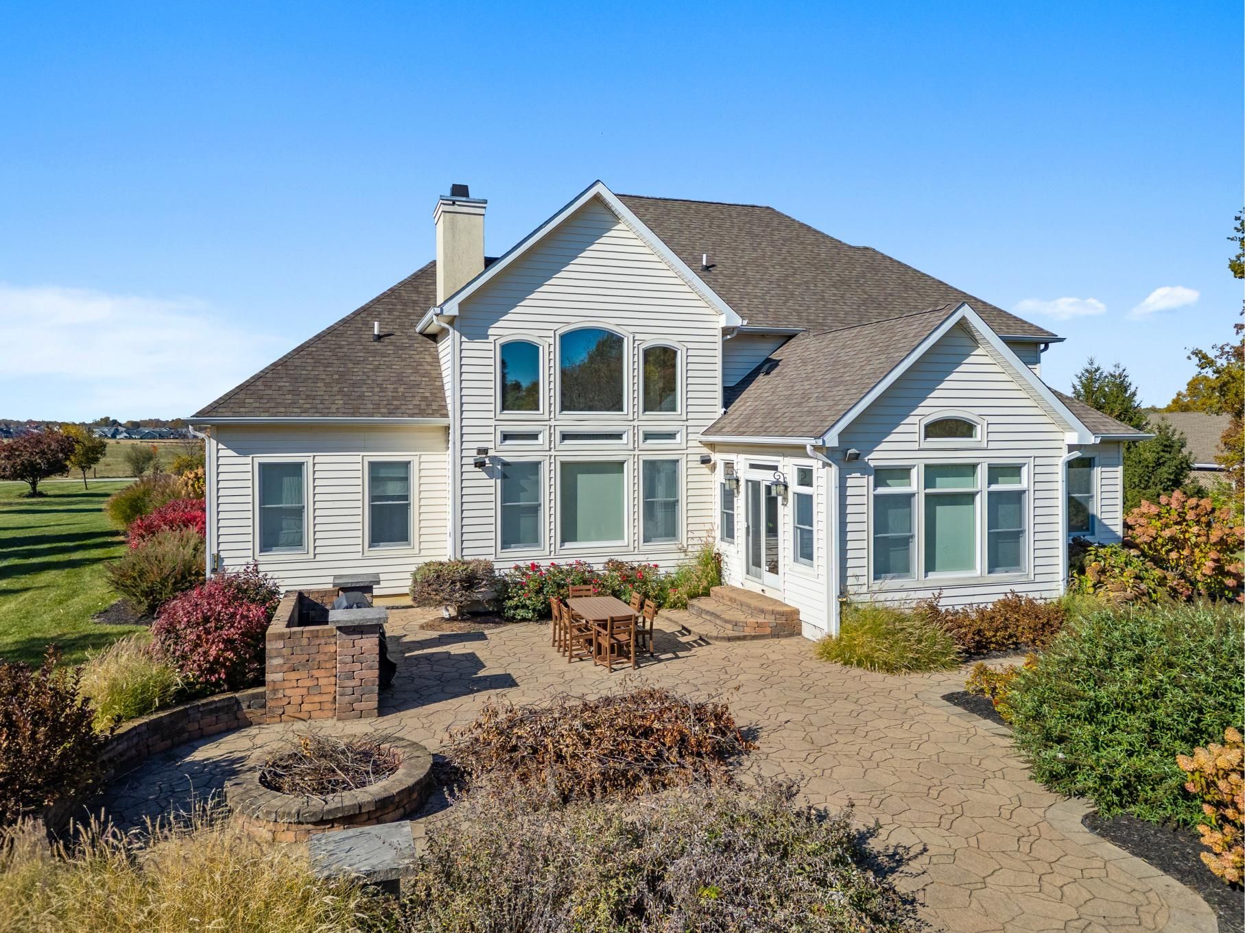 Single-story gray house with stone accents and landscaped yard under a clear blue sky