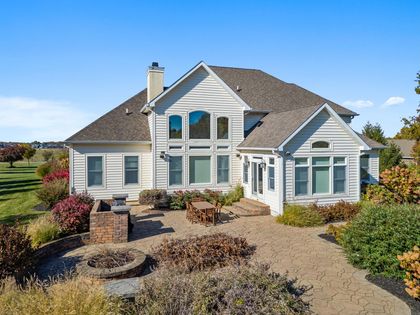 Suburban beige house with a landscaped front yard under a clear blue sky