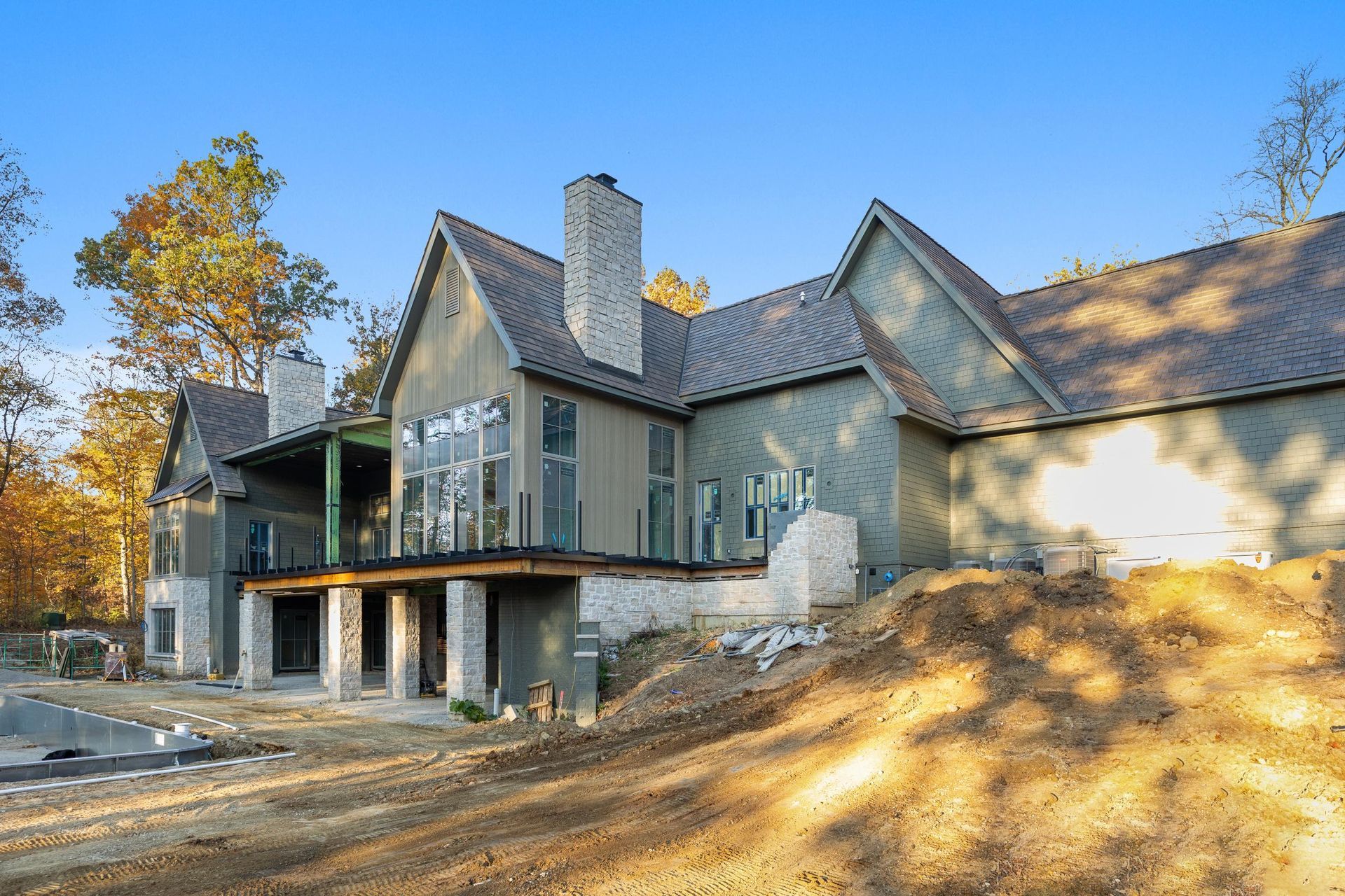 Modern gray house with gabled roof and deck on a wooded hillside under construction