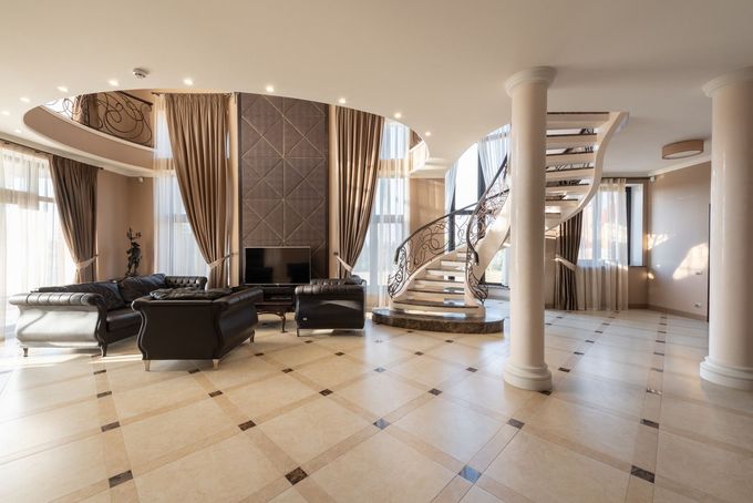 Elegant modern hotel lobby with curved staircase, black seating, and marble floors