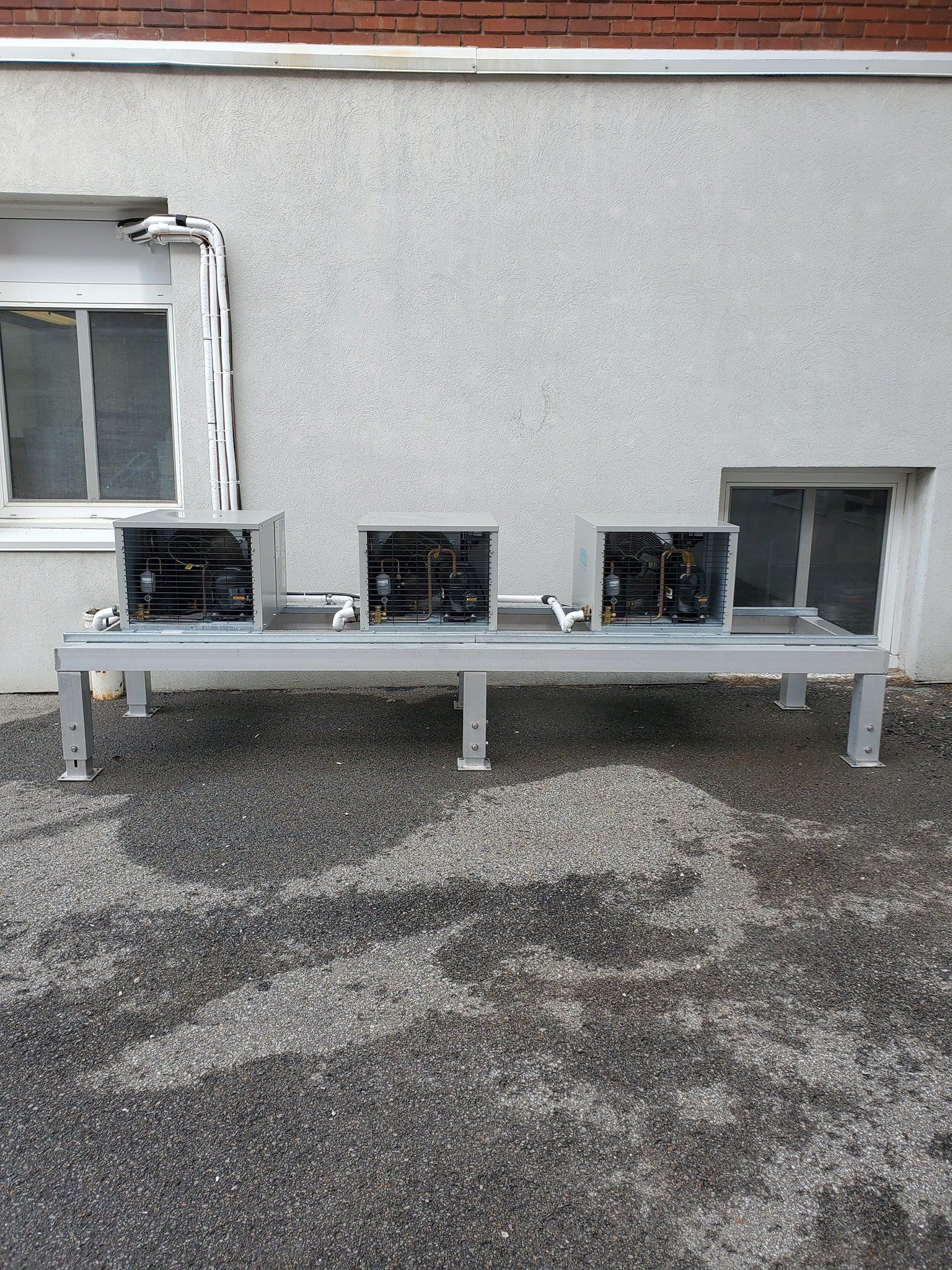 Un banc est assis devant un immeuble à côté d’une fenêtre.