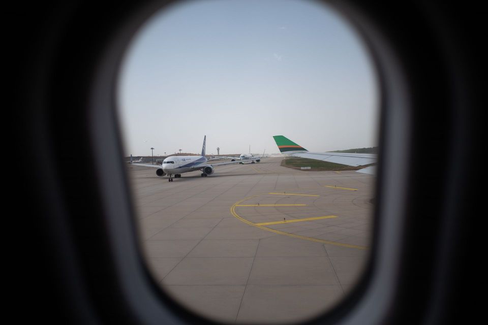 Airplane parked on airport tarmac, seen through an oval window frame