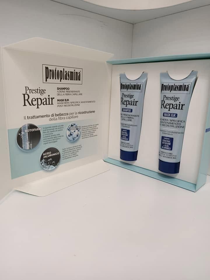 Confezione del prodotto aperta con due tubetti Prestige Repair blu e bianchi su un supporto espositivo bianco.