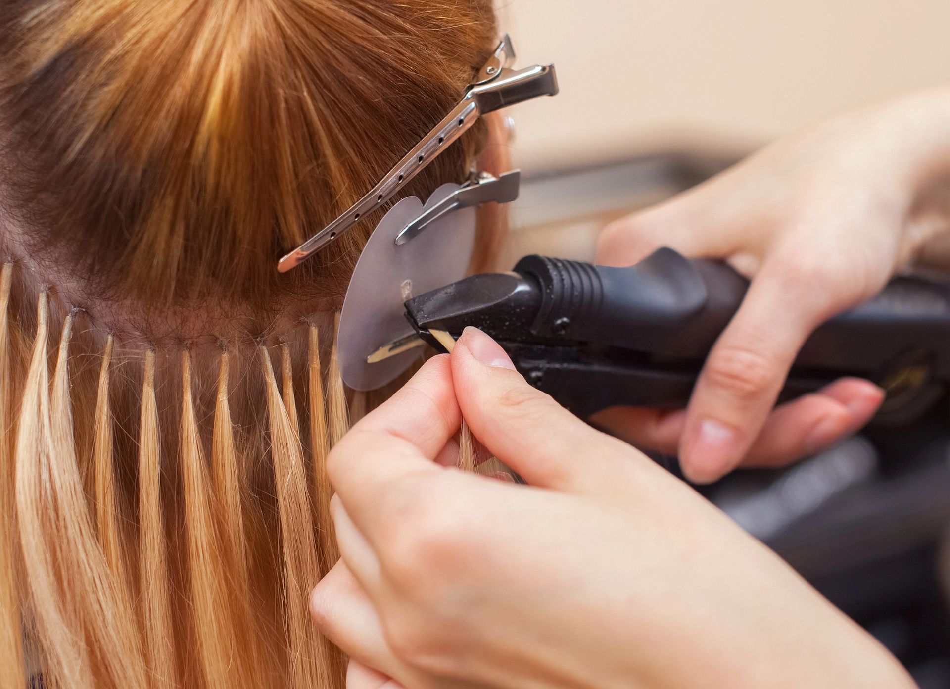 Parrucchiere che utilizza un ferro arricciacapelli e delle mollette per applicare delle ciocche di capelli castani in un salone.