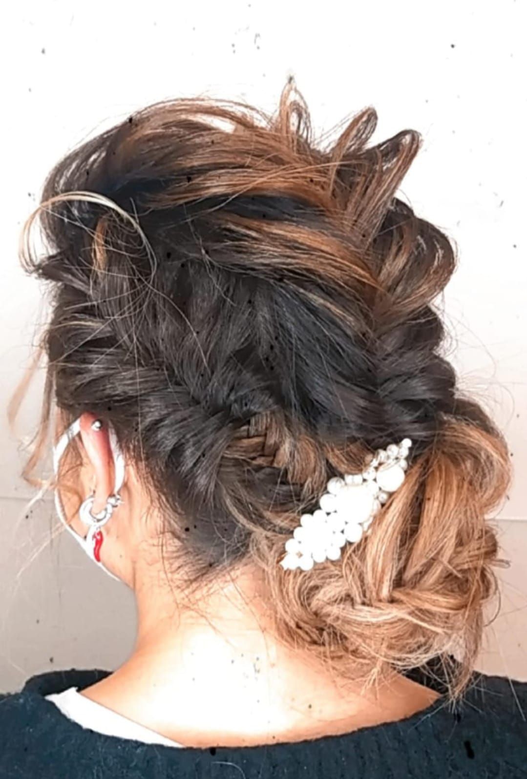 Vista posteriore di un'acconciatura raccolta con riccioli morbidi e un accessorio per capelli floreale bianco.