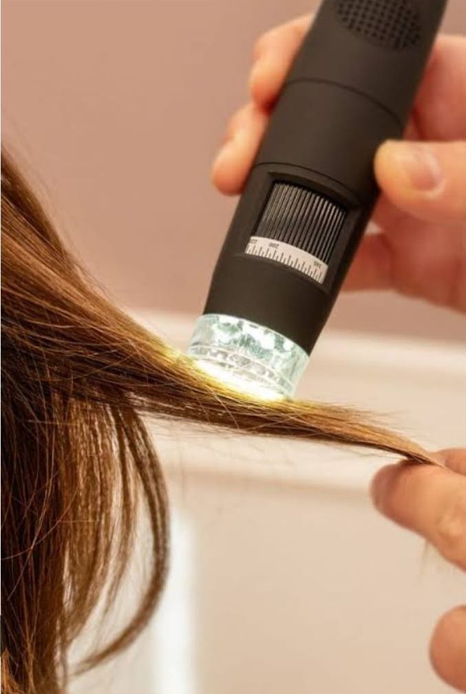 Una donna usa una torcia per esaminare da vicino i capelli.