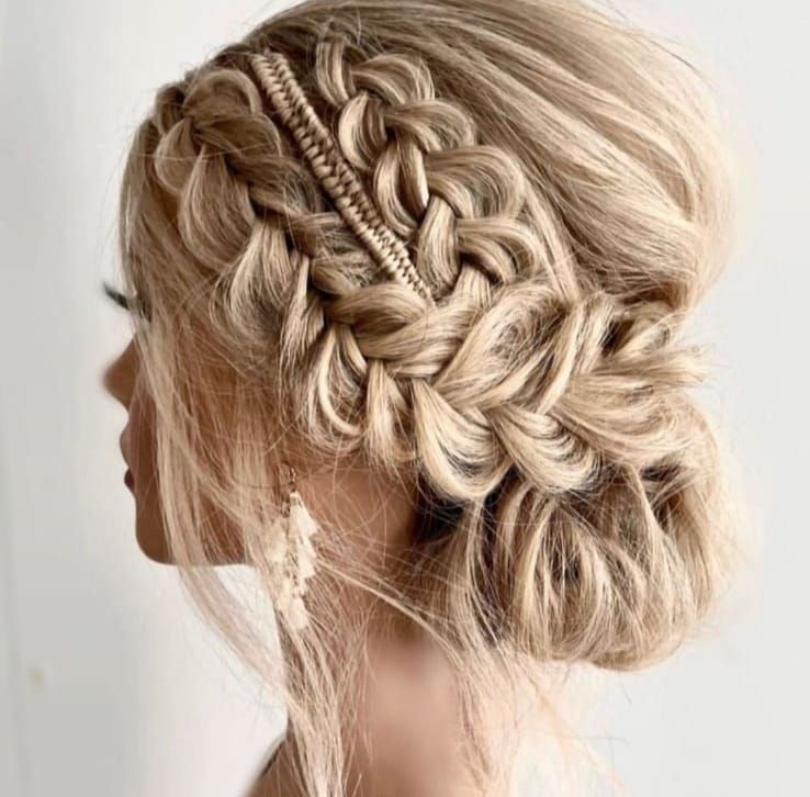 Acconciatura raccolta bionda con trecce intrecciate intricate e chignon morbido, vista laterale
