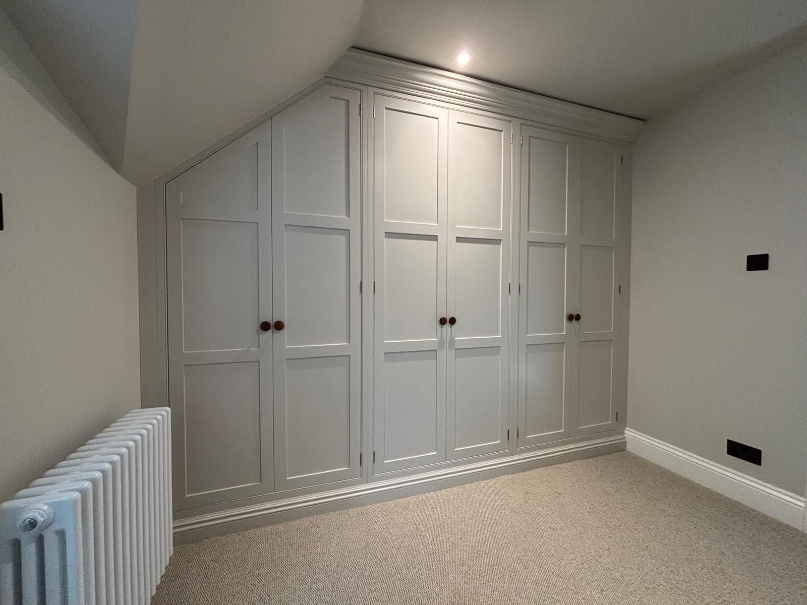 A bedroom with a lot of white cabinets and a radiator.
