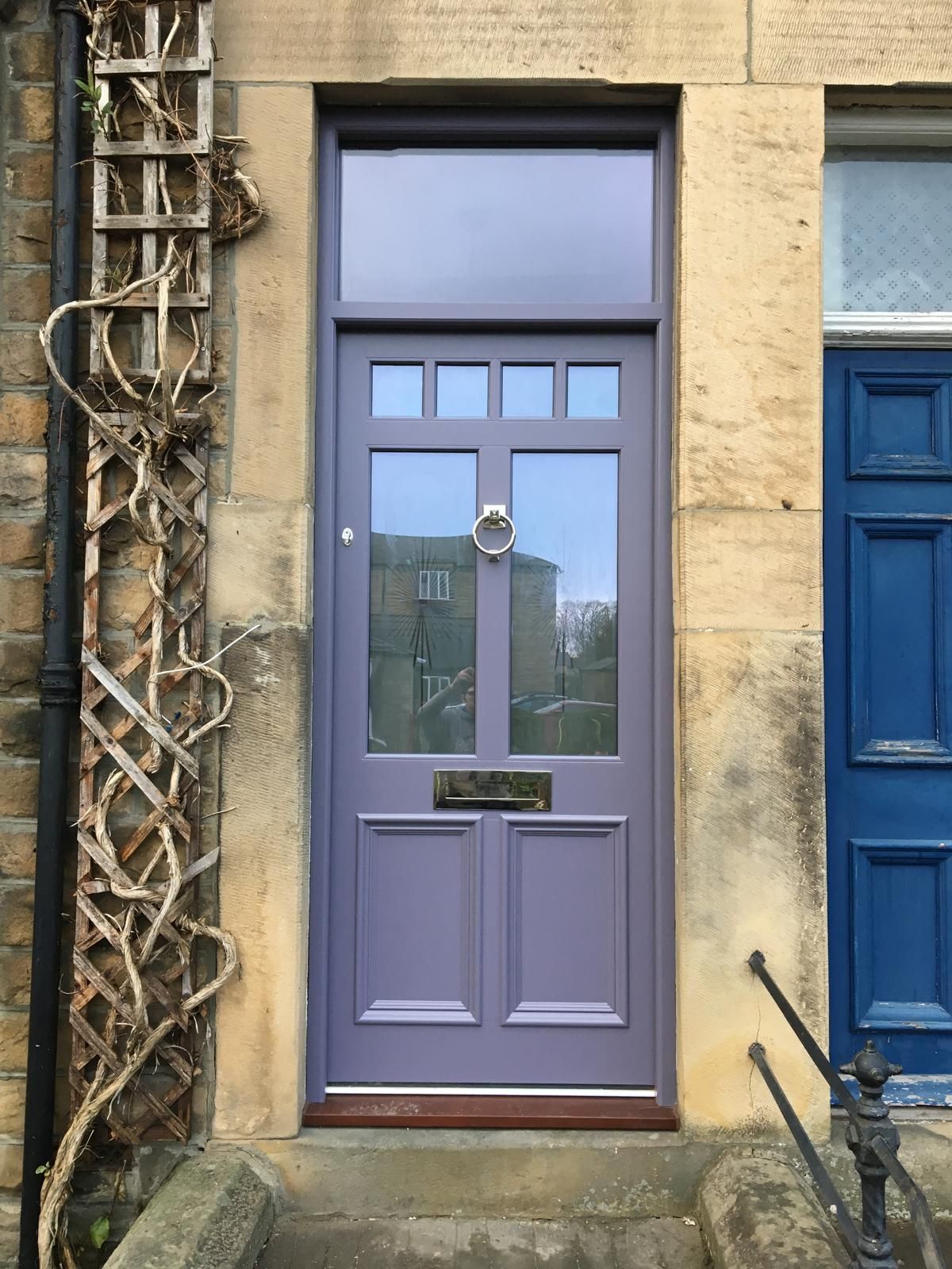 A purple door is on a stone wall next to a blue door
