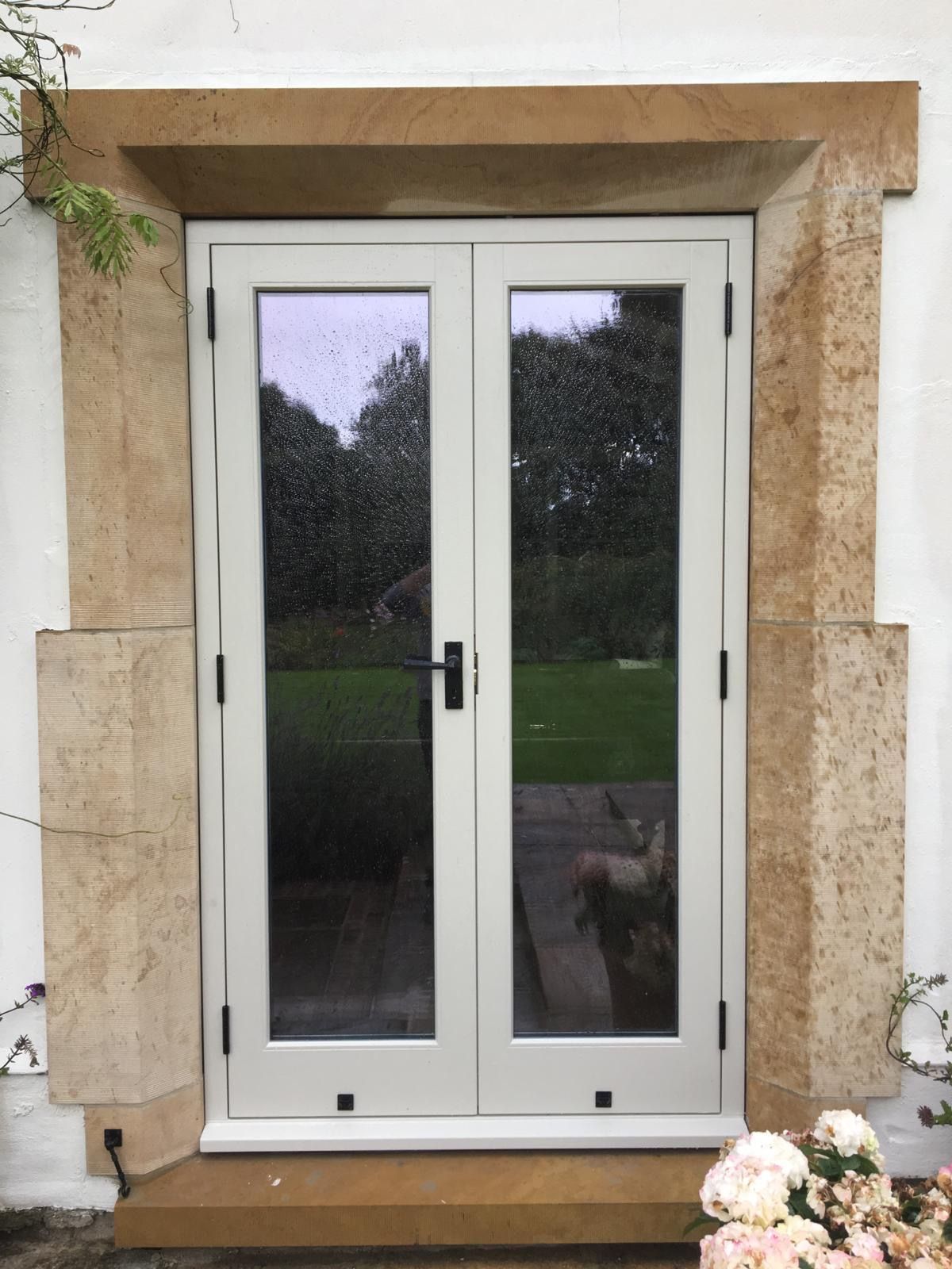 A white door with a stone frame and flowers in front of it