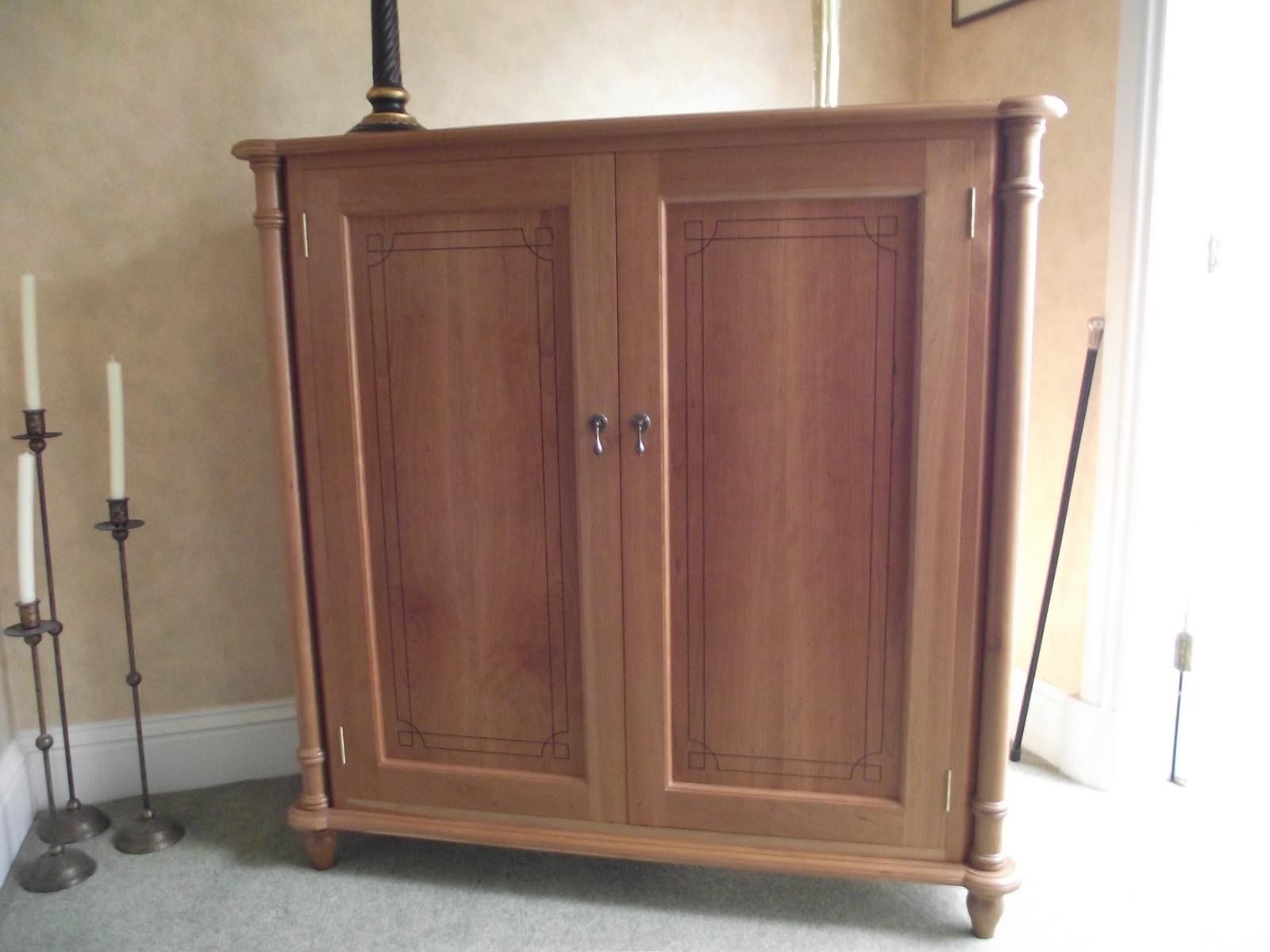A wooden cabinet with two doors sits in a room next to candles