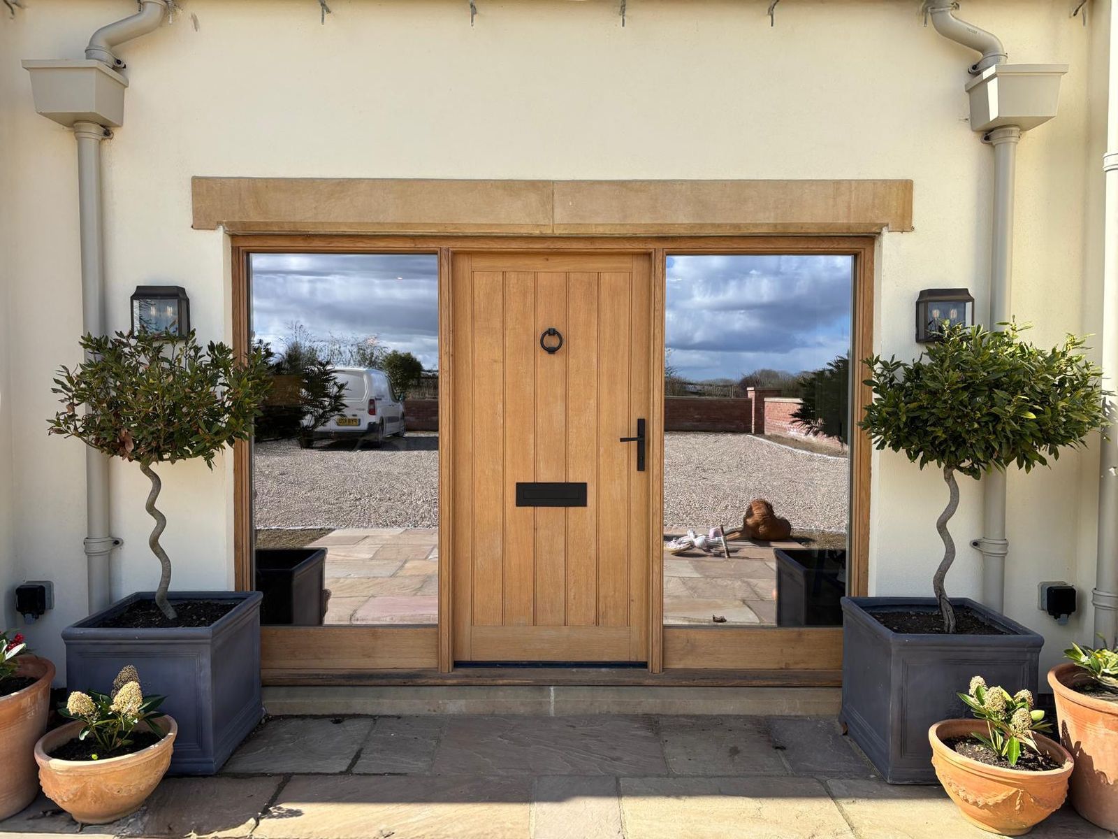 A house with a wooden door and potted plants in front of it.