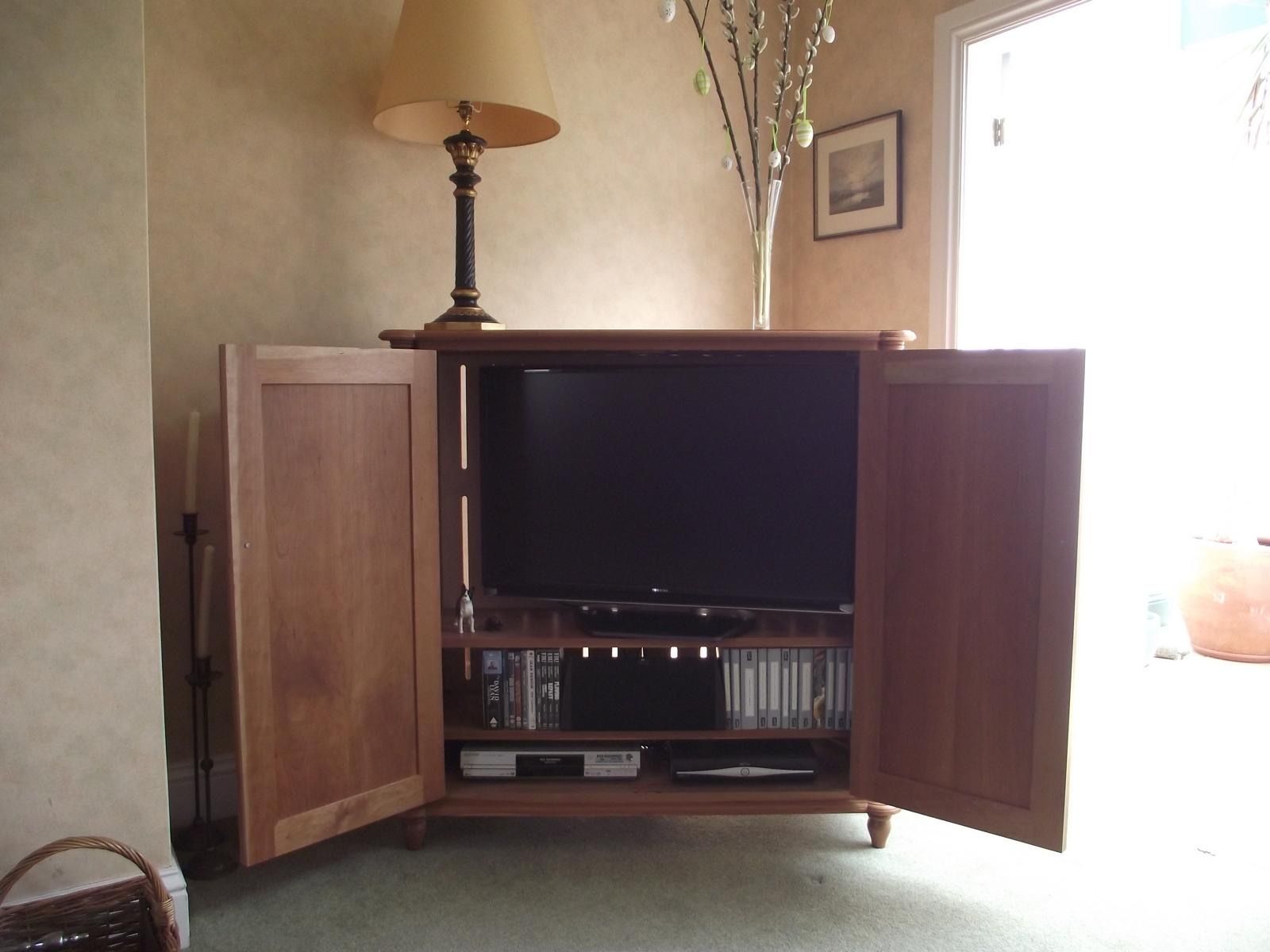 A tv is sitting inside of a wooden cabinet with the doors open