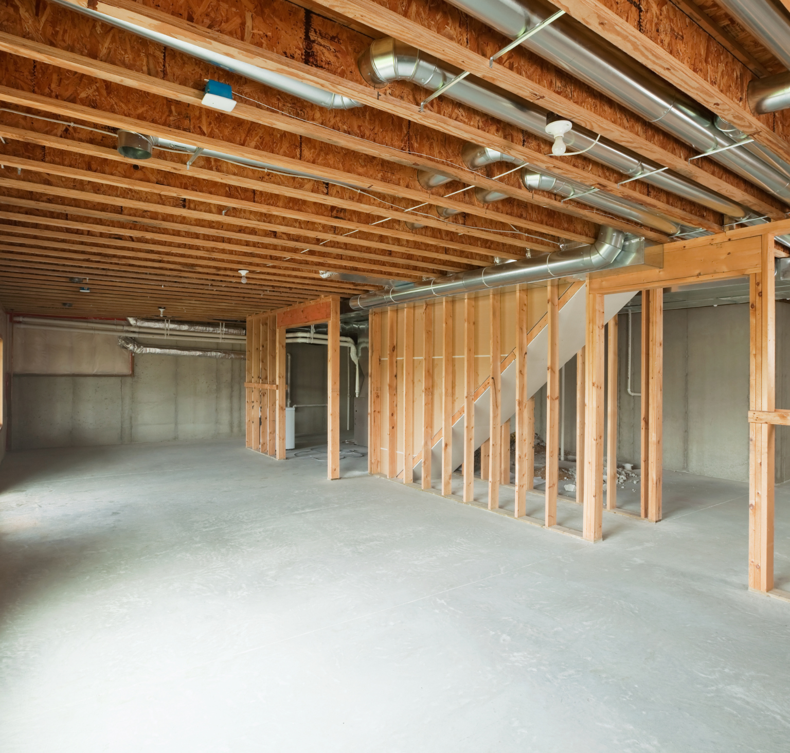 An empty basement with wooden beams and a staircase.