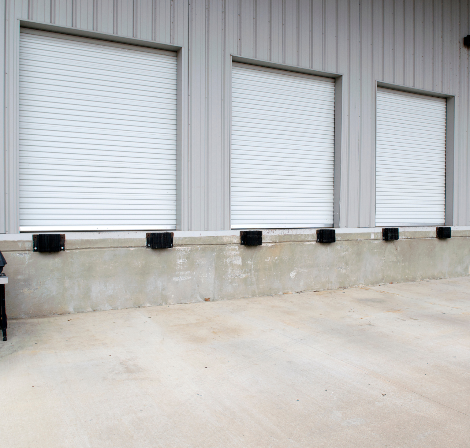 A row of white roller shutters on the side of a building.