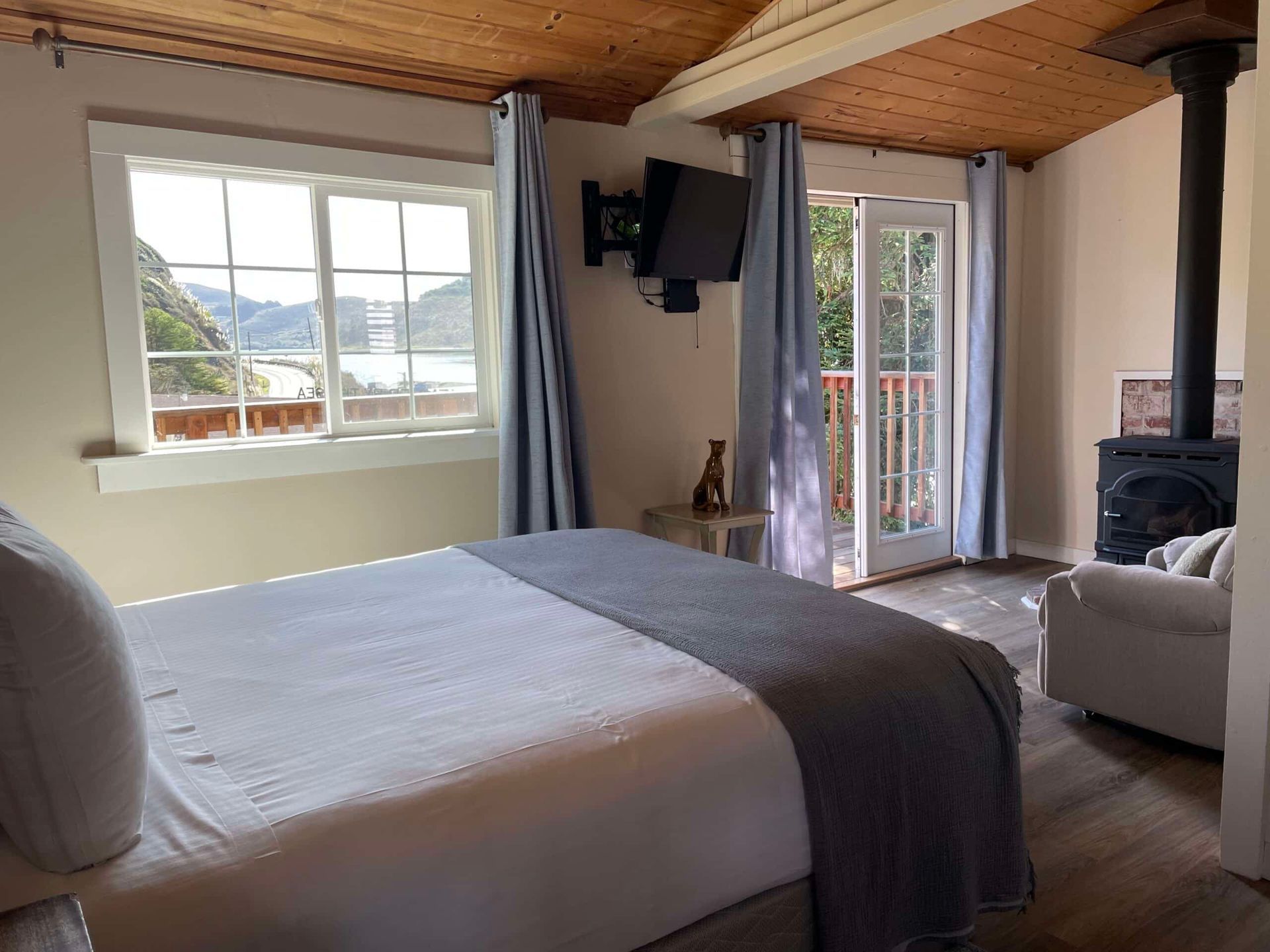 Bedroom with a bed, windows, balcony, fireplace, and a mounted television.