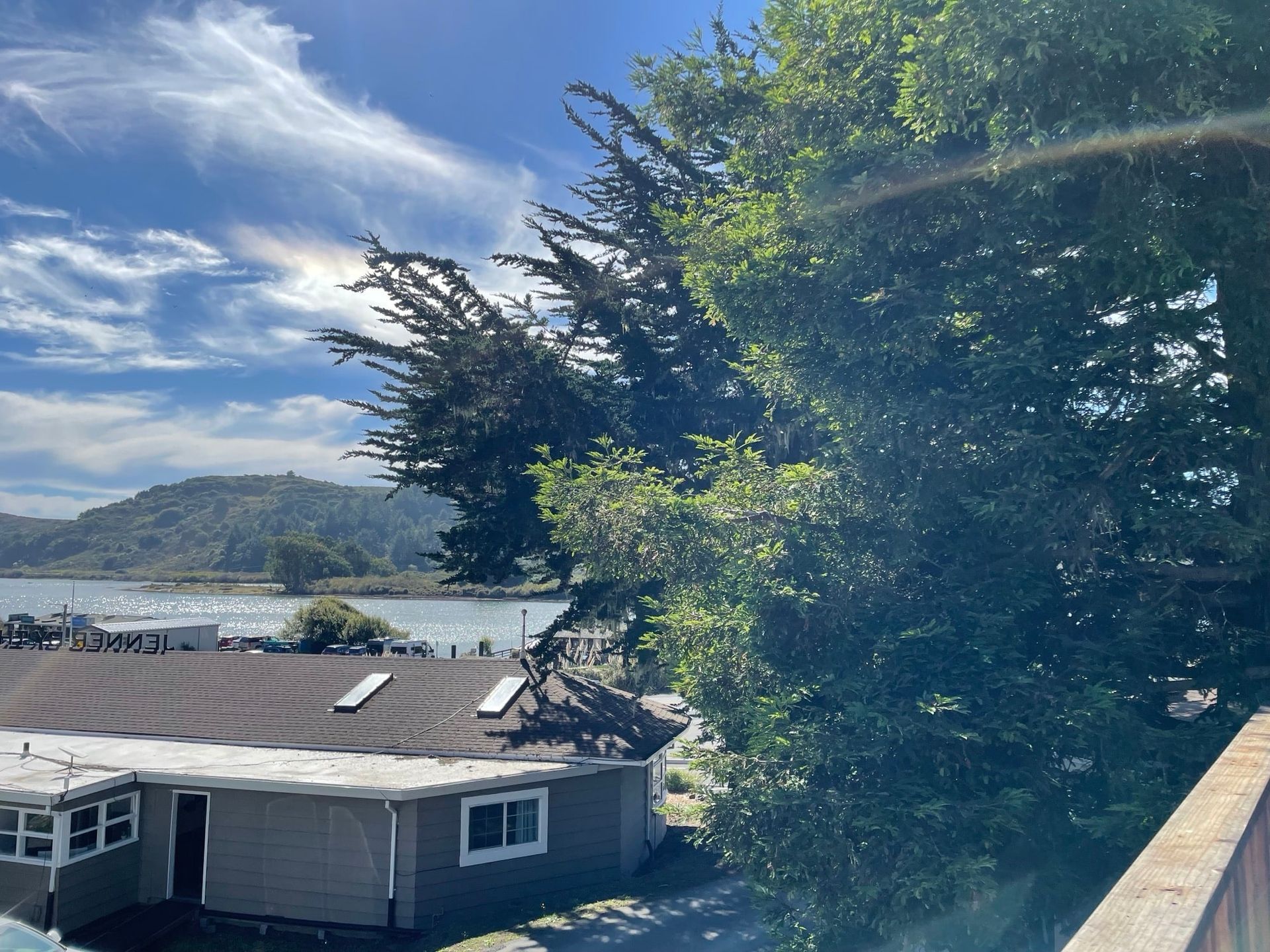 Harbor view with buildings, trees, water, boats, and a partly cloudy sky.