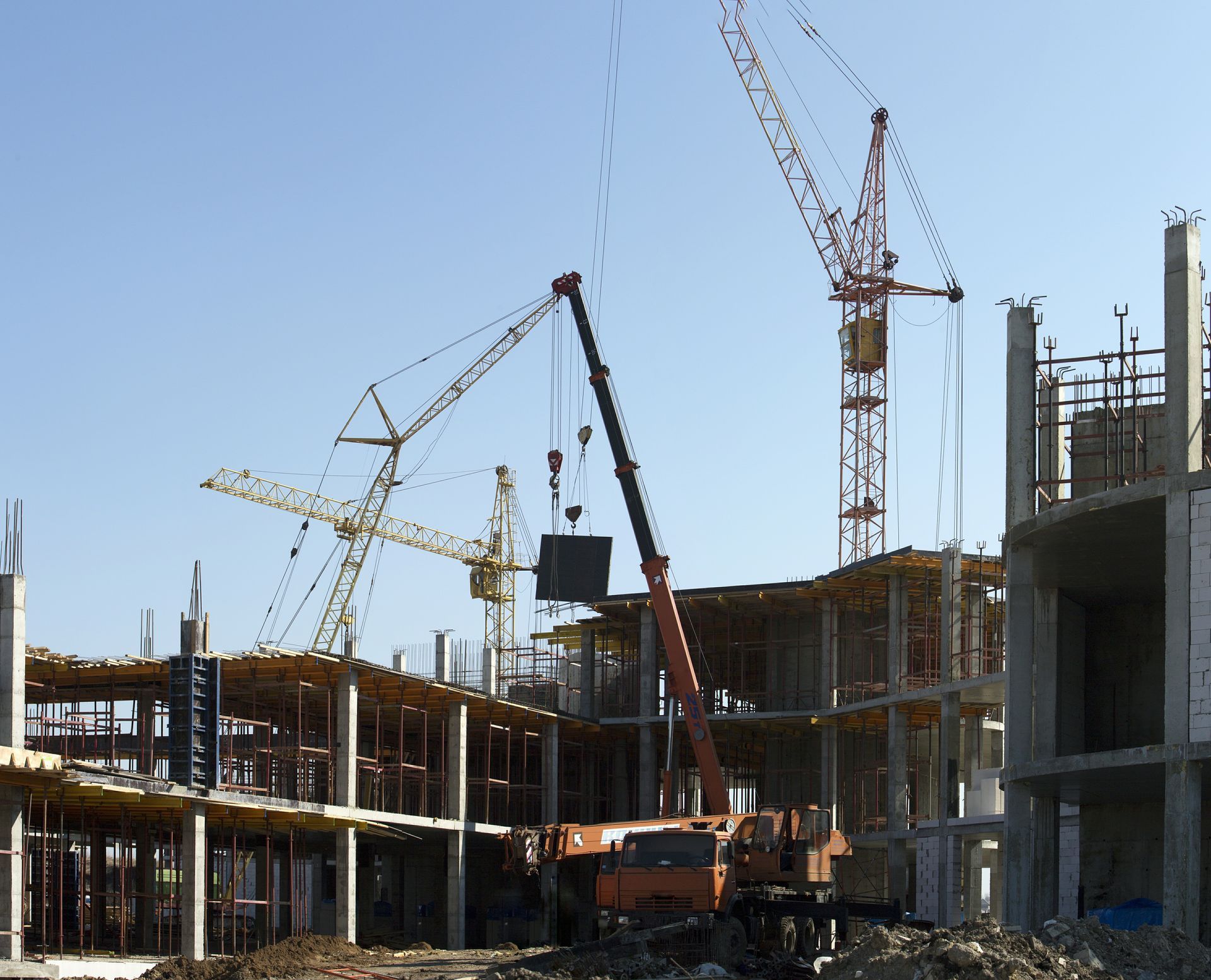 Construction site with cranes and unfinished concrete buildings under a clear blue sky