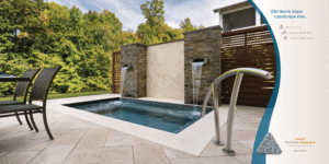 Modern backyard pool with waterfall, metal handrails, patio chairs, and greenery beyond
