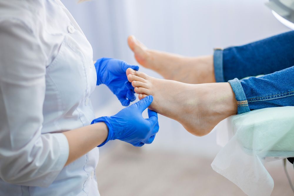 A Woman is Getting Her Feet Examined by a Doctor — Newcastle Foot & Ankle Clinic Charlestown In Belmont, NSW