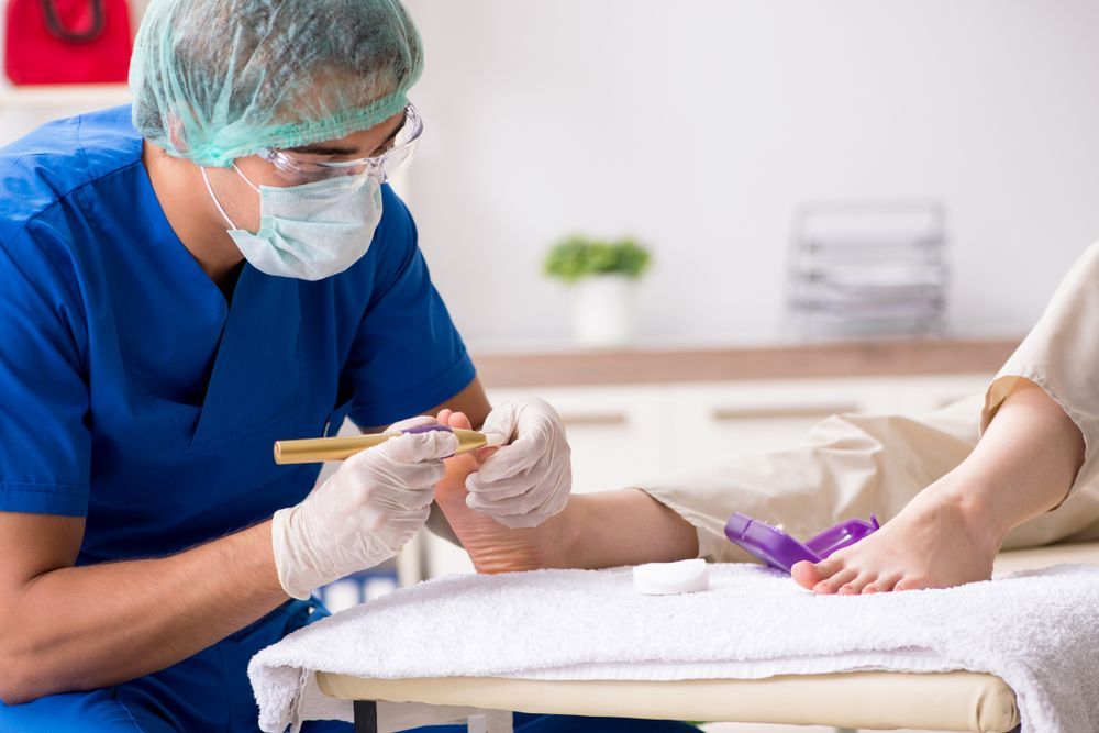 A Doctor is Examining a Patient's Foot in a Hospital — Newcastle Foot & Ankle Clinic Charlestown In Charlestown, NSW