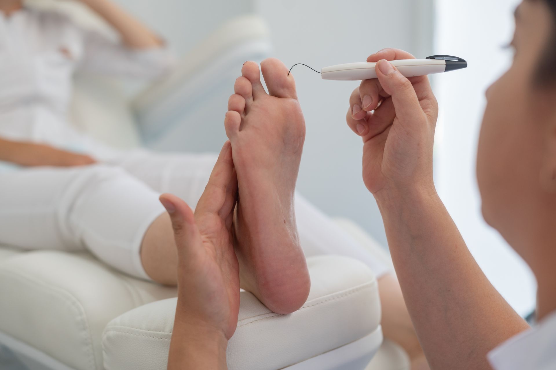 A doctor is treating on a patient 's foot with a tool — Newcastle Foot & Ankle Clinic Charlestown In Charlestown, NSW