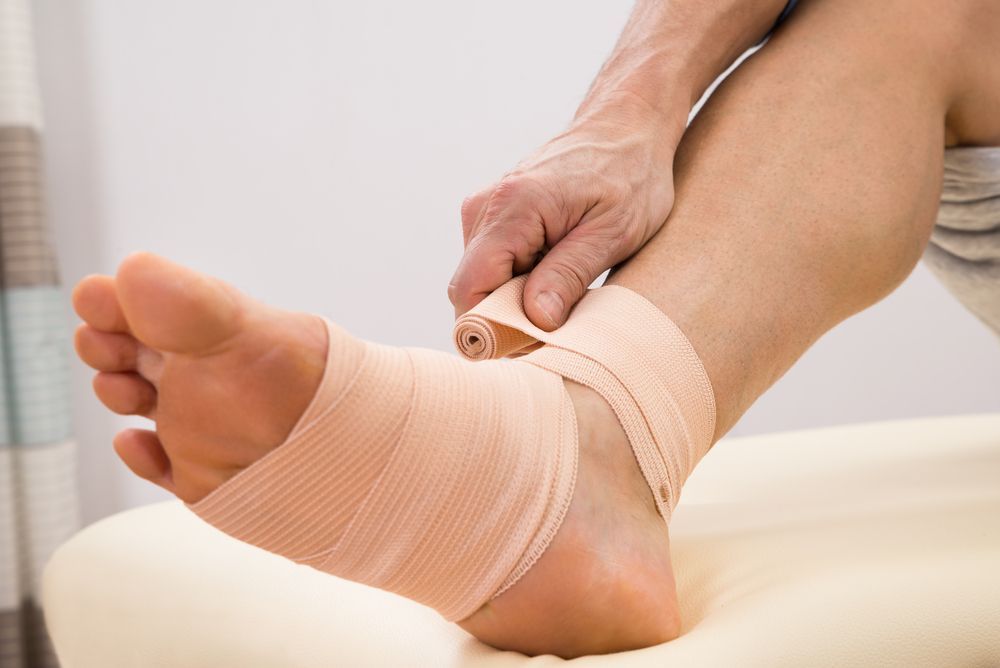 A Person is Wrapping Their Ankle With a Bandage — Newcastle Foot & Ankle Clinic Charlestown In Maitland, NSW
