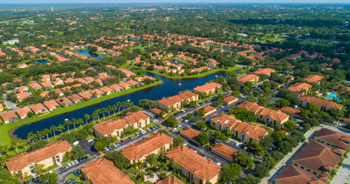 Aerial view of a suburban neighborhood with red-roofed homes and a winding canal