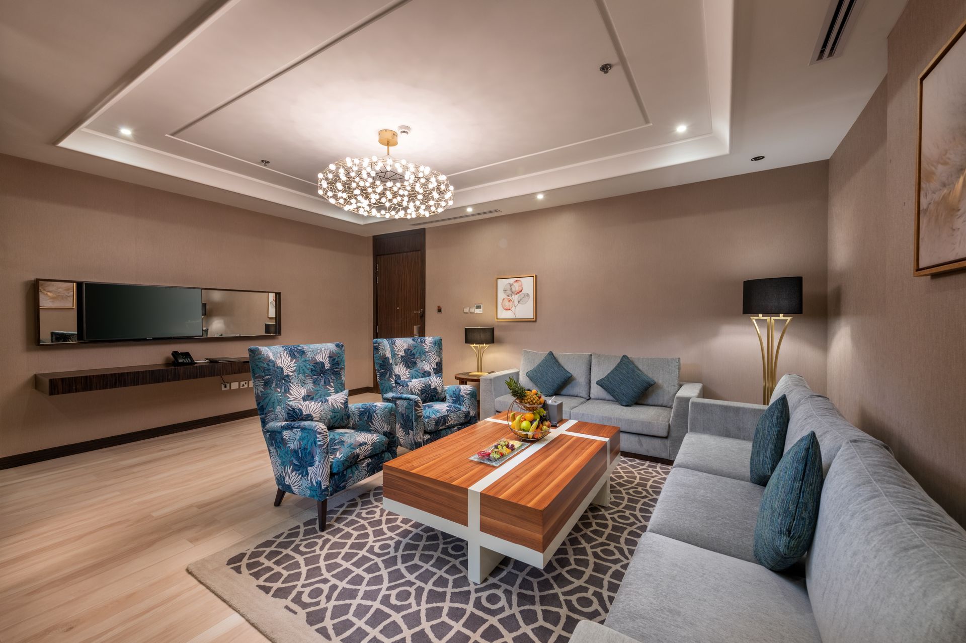 Modern living room with blue sofas, patterned chairs, a coffee table, and a chandelier