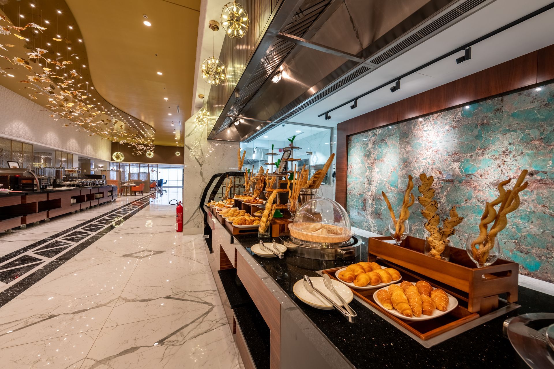 Modern restaurant buffet with pastries and breads beside a bright open dining area