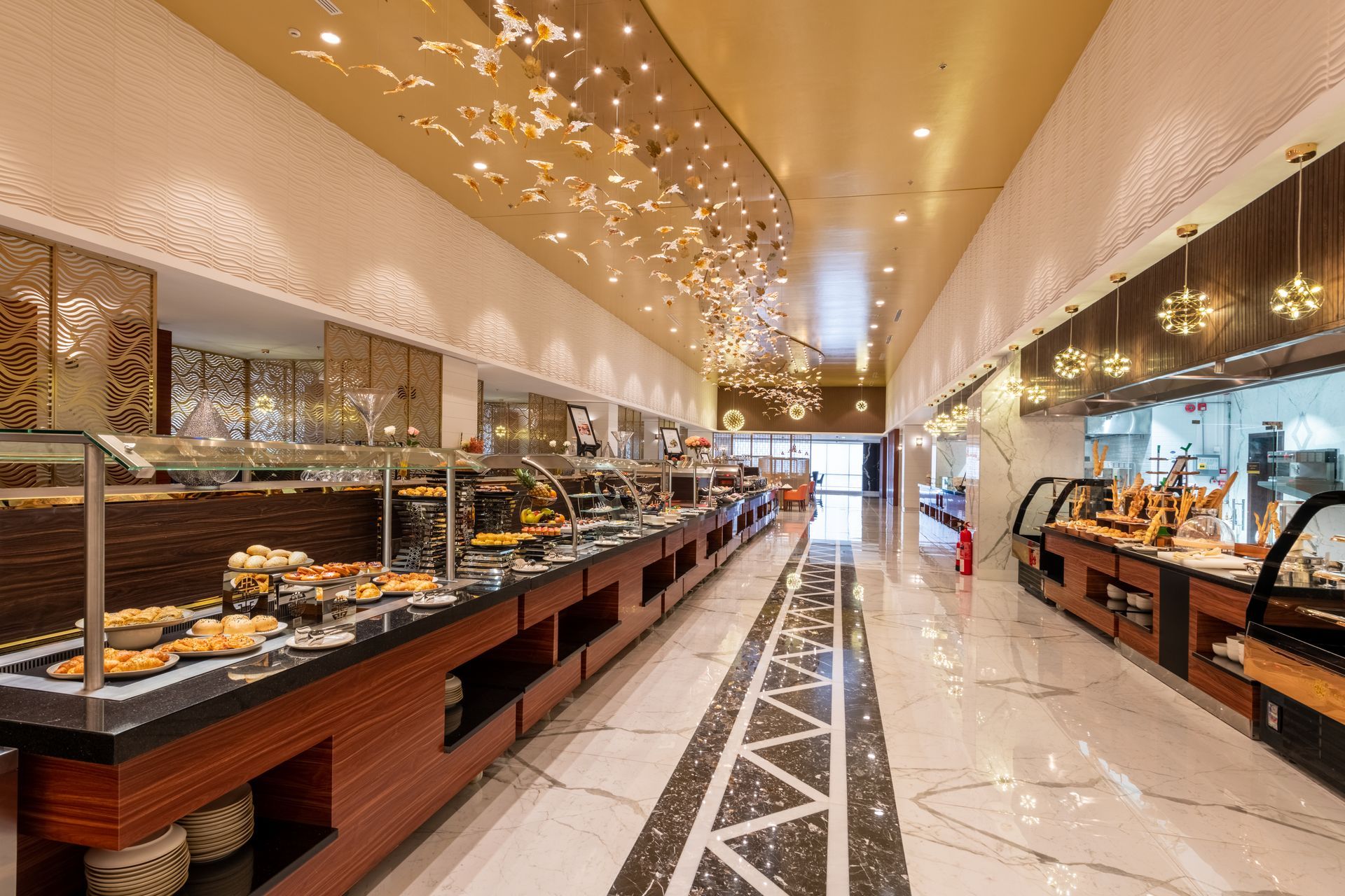 Elegant hotel buffet with long mirrored counters, warm lighting, and a glossy tiled walkway