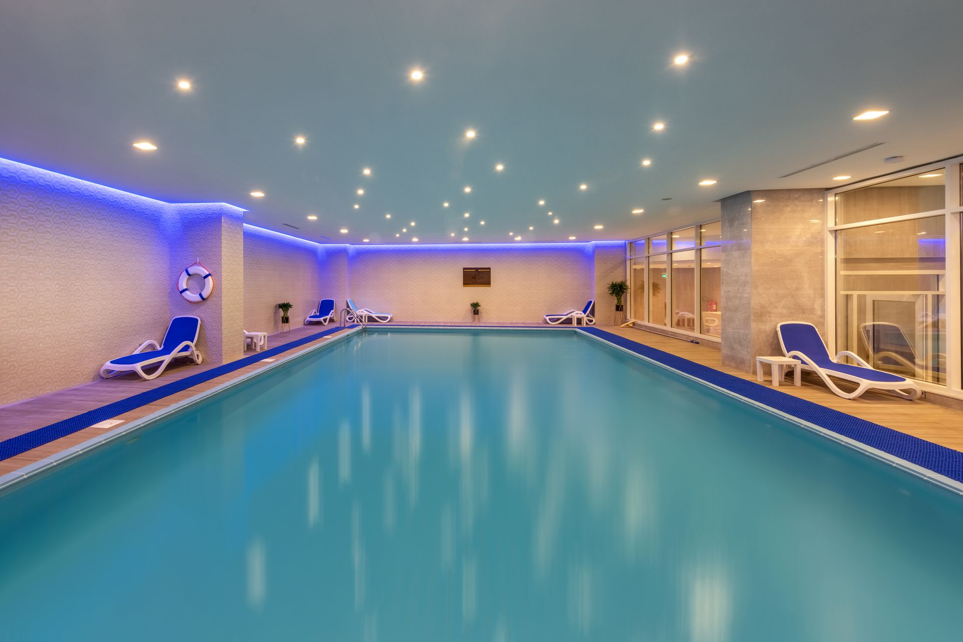 Indoor swimming pool with blue water, lounge chairs, and blue and white tile accents.