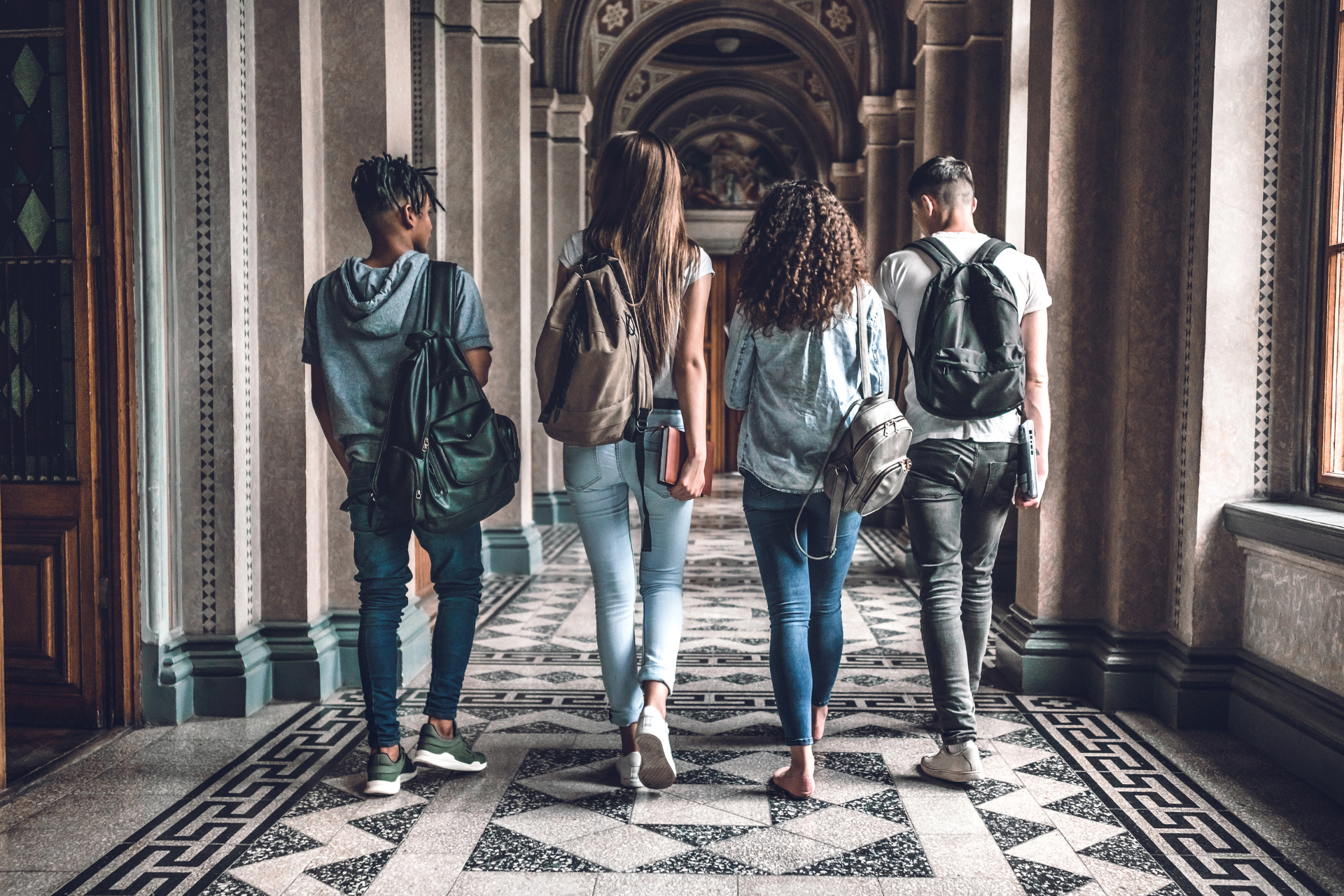 A group of young people are walking down a hallway.