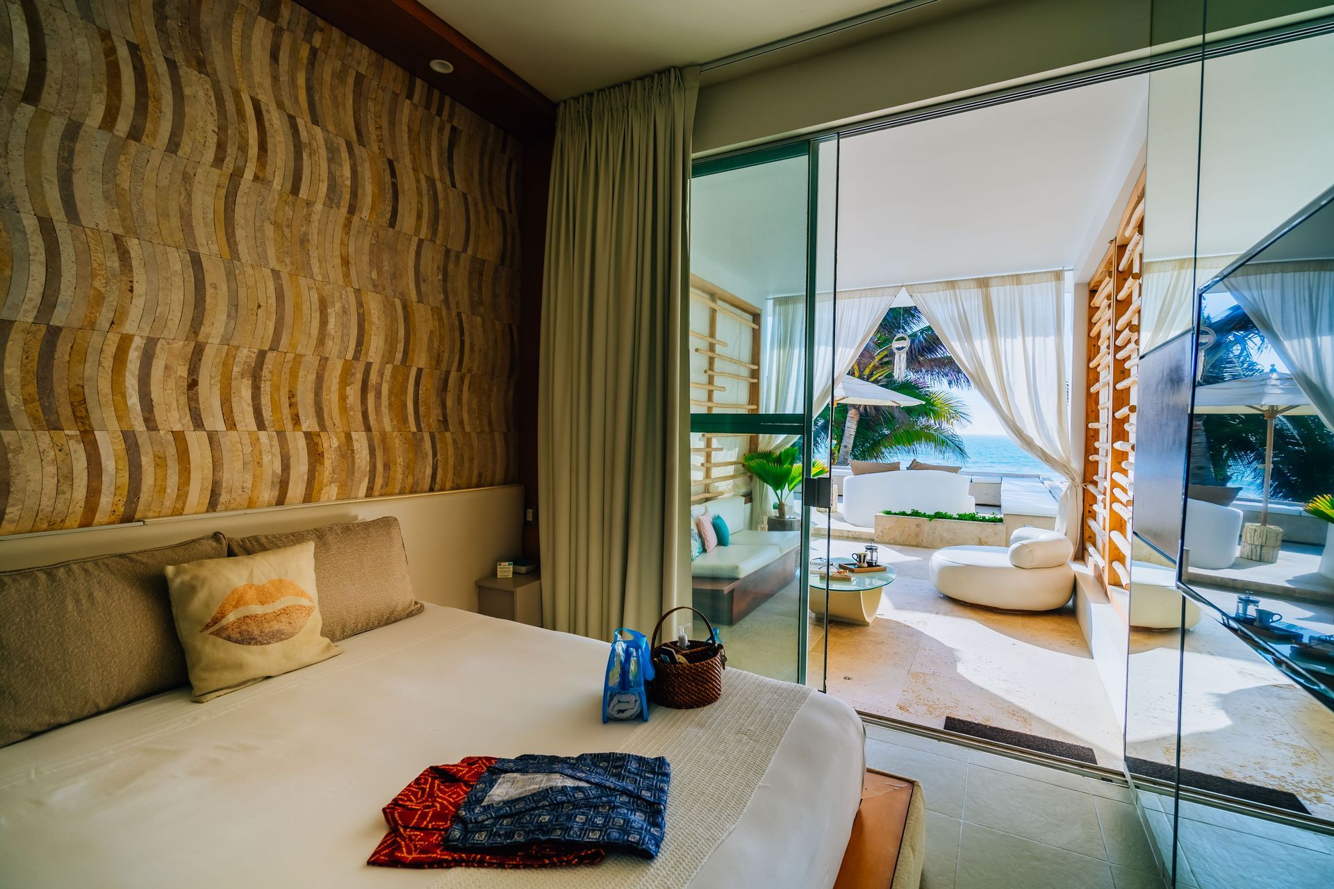 A bedroom with a large bed and a sliding glass door leading to a balcony.