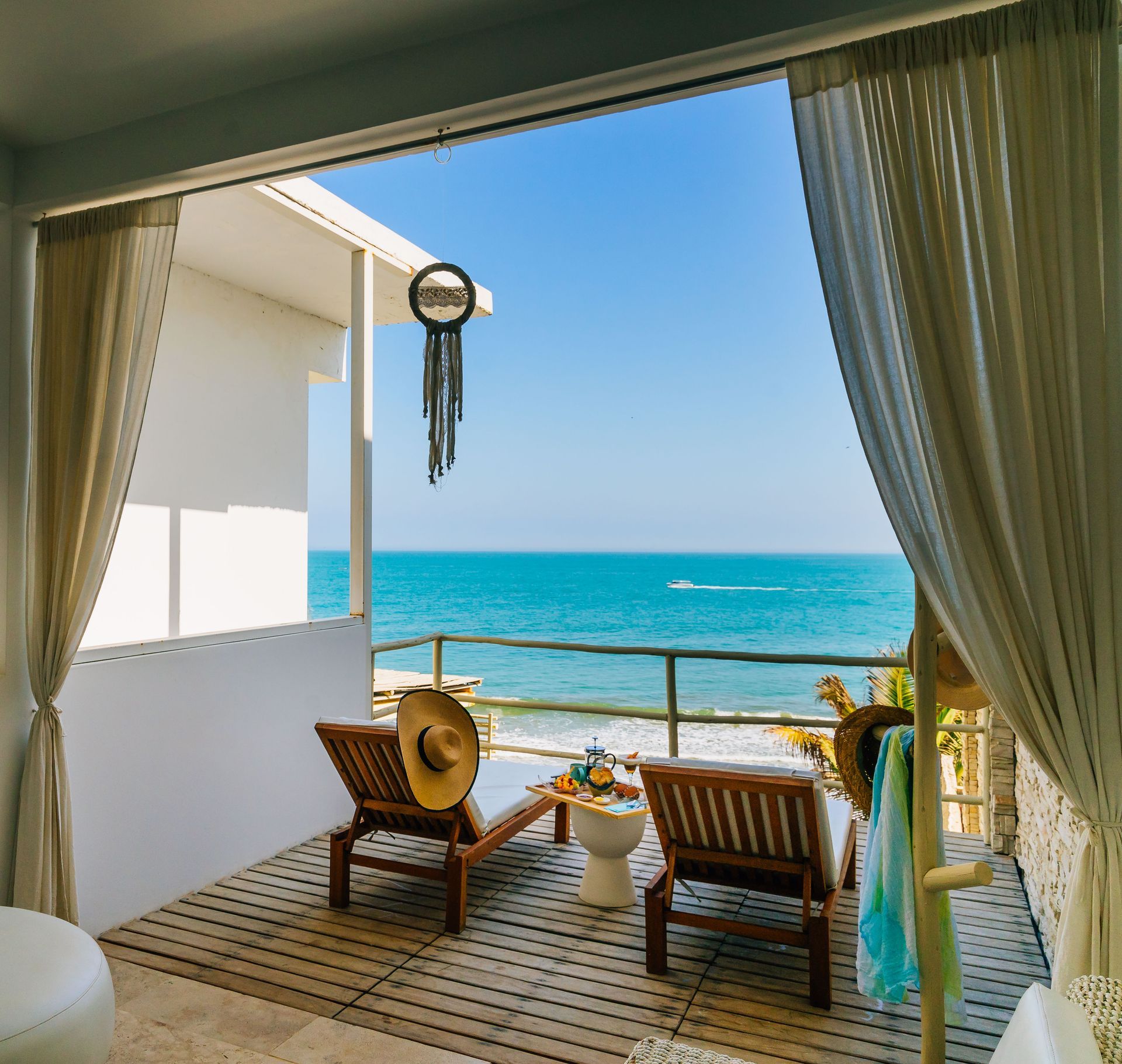 A balcony with chairs and a table overlooking the ocean