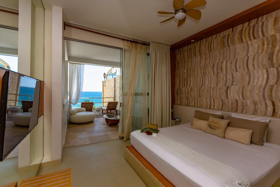 A hotel room with a king size bed , a flat screen tv , and a view of the ocean.