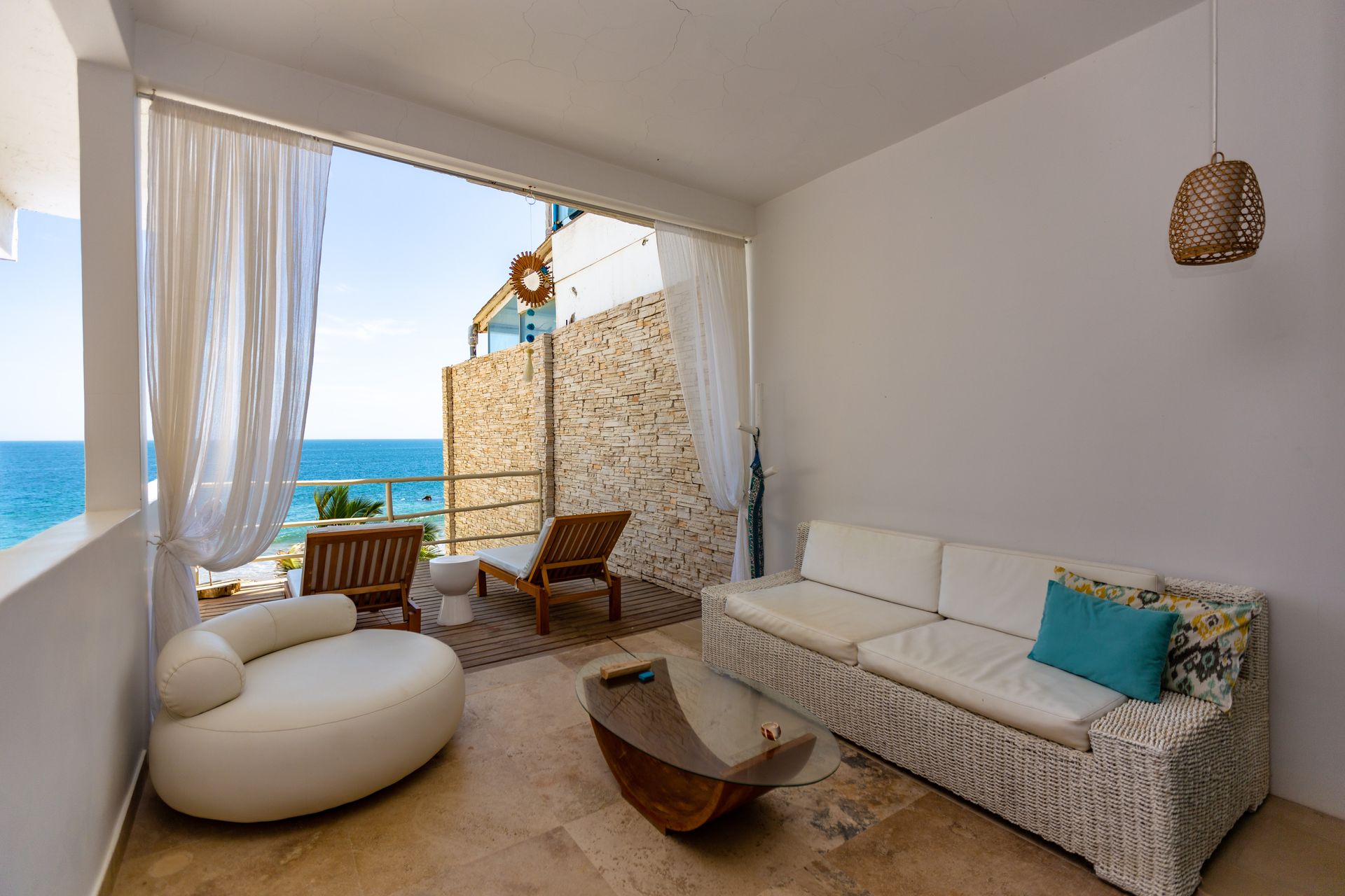 A living room with a couch , chair , and table with a view of the ocean.
