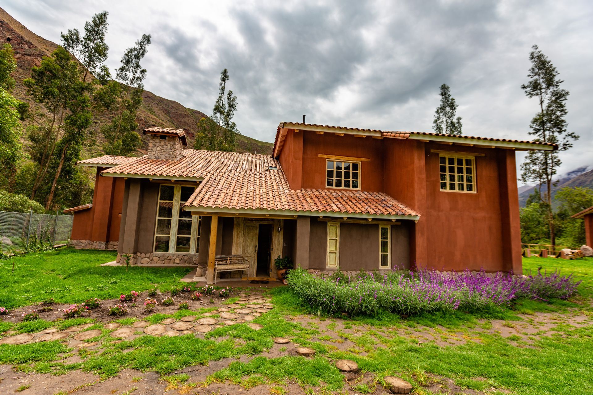 A large brown house with a tiled roof is sitting in the middle of a lush green field.
