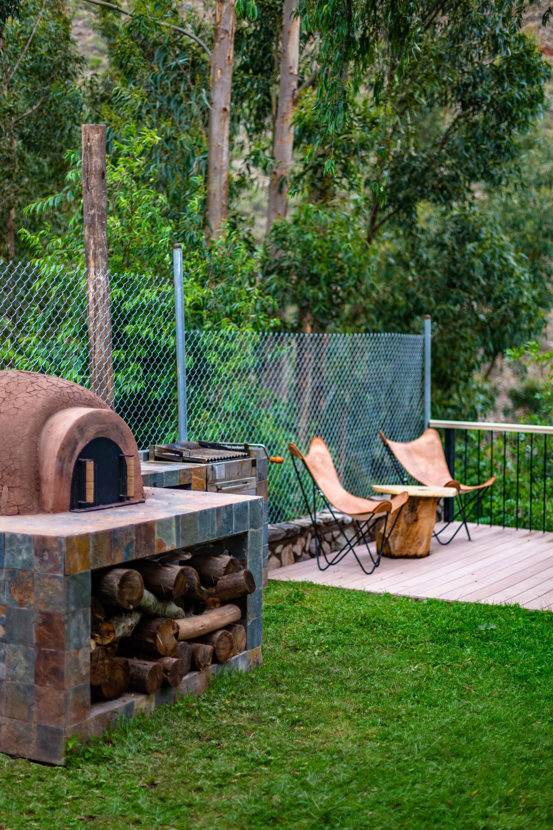 There is a wood oven in the backyard with chairs and a table.