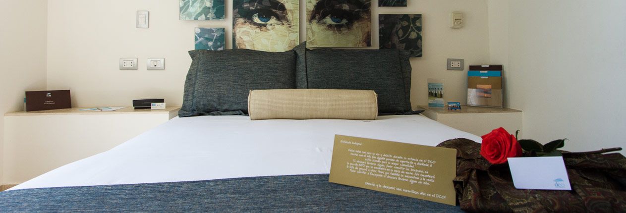 A bedroom with a bed , nightstand , and a card on the bed.