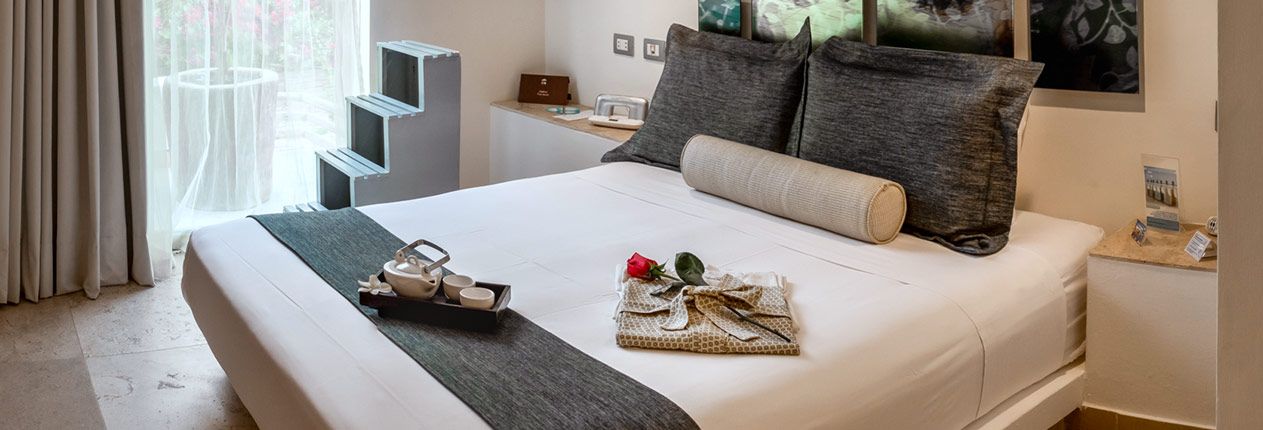 A hotel room with a king size bed and a tray on the bed.