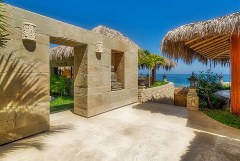 A stone building with a thatched roof next to the ocean.