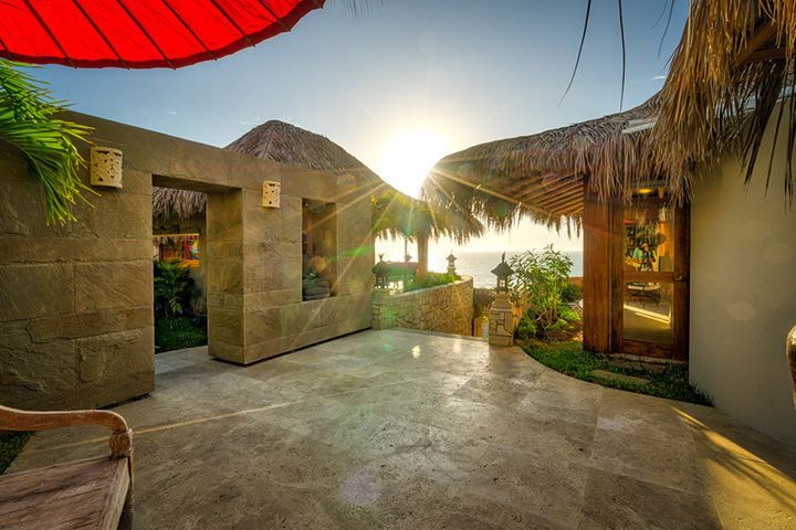 The sun is shining through the thatched roof of a building.