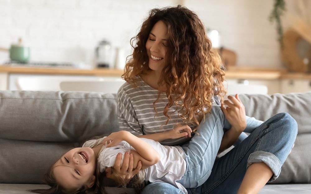 Woman and Child Laughing on a Couch — Midcoast Financial Planning Group in Tuncurry, NSW