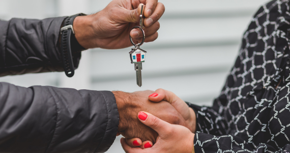Person Handing Keys, With House-shaped Keychain, To Another While Shaking Hands — Midcoast Financial Planning Group in Tuncurry, NSW