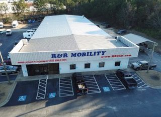 Aerial view of R&R Mobility storefront with parked vans and accessible parking spaces.