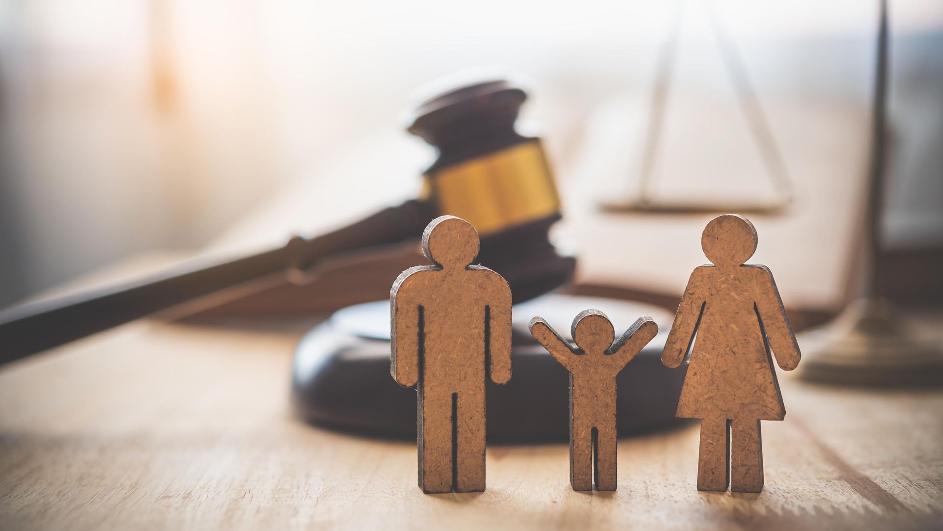 Three wooden figures before a gavel, symbolizing family law or legal judgment